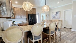 A kitchen with wooden cabinets, a black refrigerator, a dining area with four chairs, and two pendant lights. - ALL DECKED OUT - 2 Bedroom, 2 Bath, Sleeps 6 - Beach Front! (Crystal Beach)