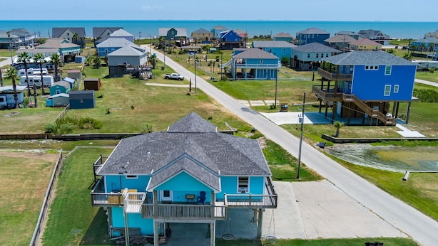 Une zone résidentielle côtière avec des maisons, une route et une plage en arrière-plan.