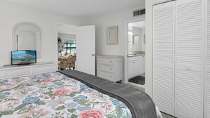 A bedroom with a bed, dresser, mirror, and closet. - Riverside Club 1 Bed Overlooking Marco River (Marco Island)
