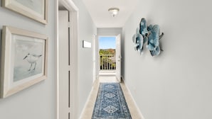 A hallway with framed artwork, a blue patterned rug, and butterfly wall art. - Marco Retreat I Direct Beach Access Across Street (Marco Island)