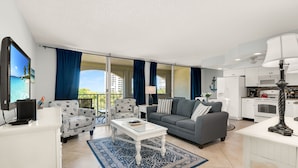 A spacious living area with a grey sofa, patterned armchairs, a white coffee table, and a kitchen in the background. - Marco Retreat I Direct Beach Access Across Street (Marco Island)