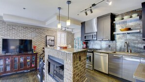 Una cocina moderna con chimenea de piedra, electrodomésticos de acero inoxidable y un televisor de pantalla plana.