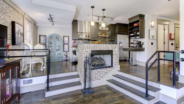 Amplia sala de estar con chimenea, cocina moderna y una escalera que conduce a otro nivel.