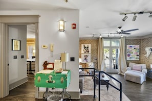 Un salon spacieux avec un coffre de rangement vert, un ventilateur de plafond et un mur en briques.