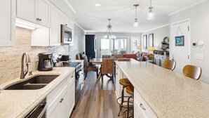 A modern kitchen with white cabinets, a granite countertop, and a central island with bar stools. - Oceanfront Wild Dunes villa-beach access, community pool & screened porch! (Isle of Palms)