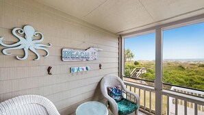 A balcony with wicker furniture, a beach-themed sign, and a view of the beach. - Oceanfront Wild Dunes villa-beach access, community pool & screened porch! (Isle of Palms)
