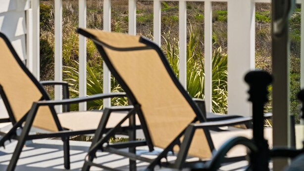 A balcony with two chairs facing a beach view. - Oceanfront Wild Dunes villa-beach access, community pool & screened porch! (Isle of Palms)