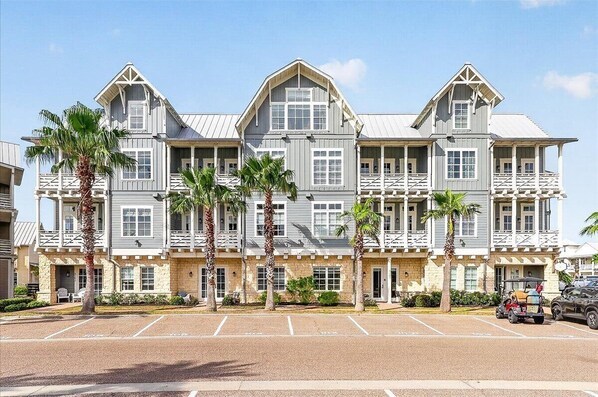 A multi-story hotel with a symmetrical facade, balconies, and a parking lot.