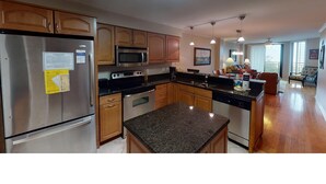 A modern kitchen with stainless steel appliances, wooden cabinets, and a granite countertop. - Shipwatch A 203: Beautiful Wild Dunes Condo with Ocean Views (Isle of Palms)