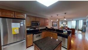 A modern kitchen with stainless steel appliances, wooden cabinets, and a granite countertop. - Shipwatch A 203: Beautiful Wild Dunes Condo with Ocean Views (Isle of Palms)
