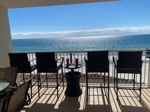 A balcony with a view of the ocean, featuring four wicker chairs, a small round table, and a trash can. - Sandy Key 538: 3 BR / 2 BA Gulf Front Condo in Perdido Key, FL Sleeps 8 (Pensacola)
