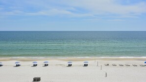 Une plage de sable blanc, une mer calme et plusieurs parasols bleus.