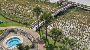 Une plage avec une promenade en bois, une piscine et des parasols.