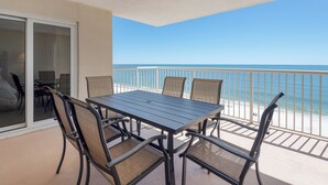 Ein Balkon mit Tisch und Stühlen mit Blick auf einen Strand.