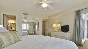 Een hotelkamer met een groot bed, een televisie, een bureau met een lamp en een spiegel.