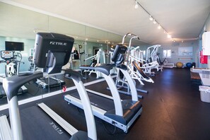 A gym with multiple treadmills, exercise machines, and a large mirror wall. - Sandy Key 534: 2 BR / 2 BA Gulf Front Condo in Perdido Key, FL. Sleeps 6 (Pensacola)