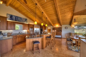 A spacious kitchen with wooden cabinetry, a central island with bar stools, and pendant lighting.