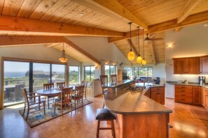 A spacious kitchen with a large island, wooden cabinets, and a view through the windows.