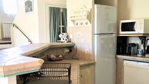 Eine Küche mit Kühlschrank, Mikrowelle und einer abgehängten Topfhalterung.