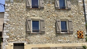 Ein Gebäude aus Stein mit mehreren Fenstern und einer Tür.