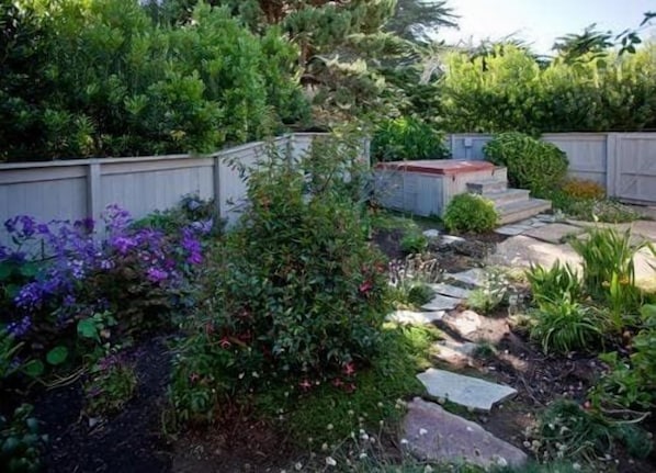 Ein Garten mit einem Kiesweg, einem Holzzaun und verschiedenen Pflanzen.