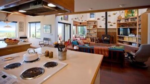 Une cuisine équipée d’une cuisinière, un coin repas avec une table et un salon avec une cheminée.