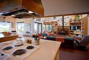 A kitchen with a stove, a dining area with a table, and a living room with a fireplace. - Brown-Hansen - Whitewater Sea Ranch Escape (Sea Ranch)