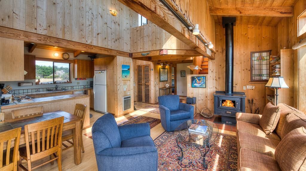 A wooden interior with a dining area, living room, and a fireplace.