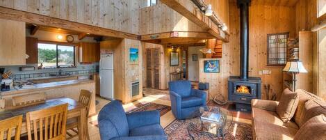 A wooden interior with a dining area, living room, and a fireplace.