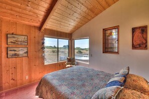 Ein Schlafzimmer mit einem großen Bett, Holzwänden und Blick ins Freie.