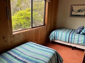 A room with two beds, wooden walls, a window, and a framed picture on the wall. - Clisham - Sea Ranch Cozy 2BR Loft Home (Sea Ranch)