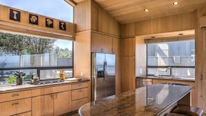 A modern kitchen with a central island, stainless steel appliances, and wooden cabinetry. - Wild Iris | Ocean View Haven with Hot Tub (Sea Ranch)