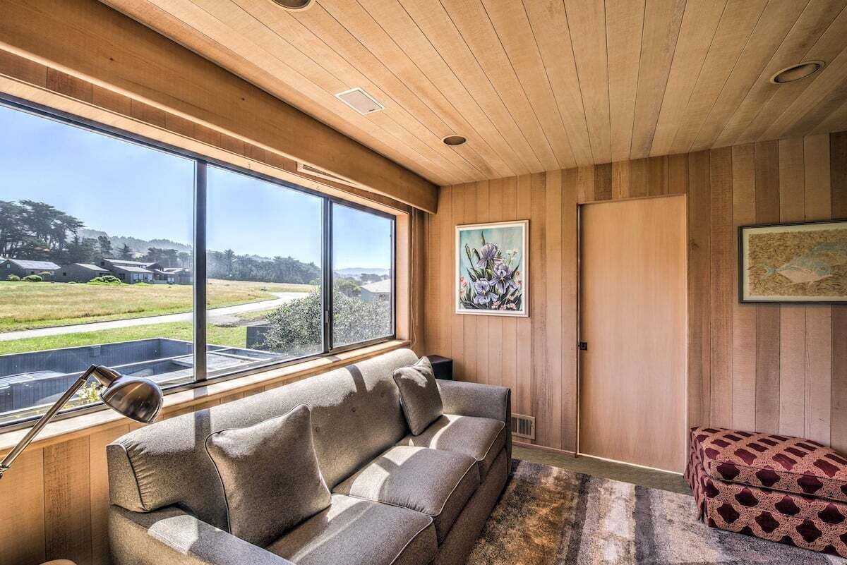 A modern interior with a wooden ceiling, large windows, a sofa, and artwork.