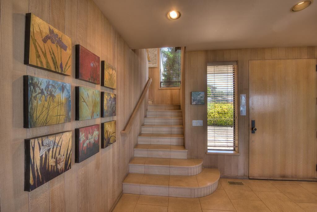A wooden staircase with a handrail, flanked by wall-mounted artwork.