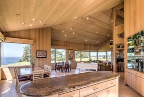 A spacious kitchen with a large island, wooden cabinetry, and a view of the ocean.