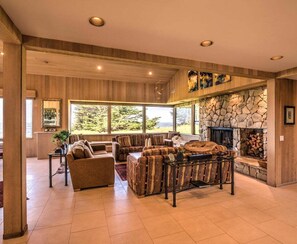 A spacious living room with a stone fireplace, large windows, and a cozy seating area.