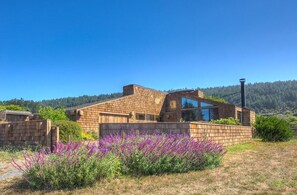 A modern house with a brick exterior, large windows, and a view of a forested hill.
