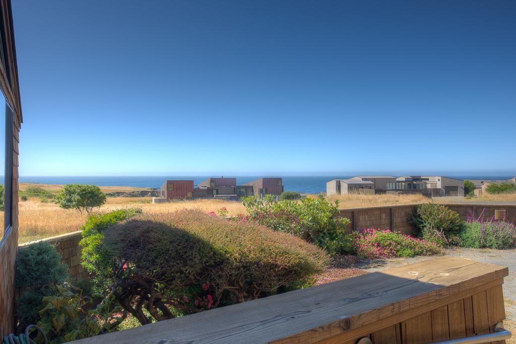 A view from a building overlooking a coastal landscape with modern structures and a wooden bench.