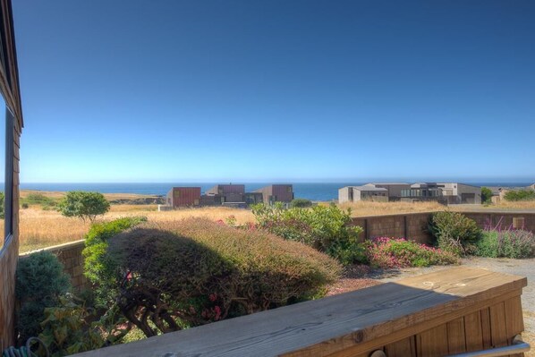 A view from a building overlooking a coastal landscape with modern structures and a wooden bench.