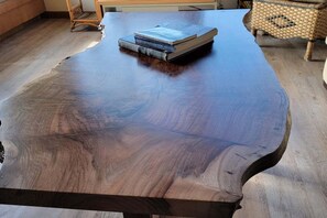 A large wooden table with a smooth finish and a stack of books on top.