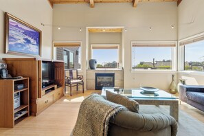 A spacious living room with a television, seating area, and large windows. - Sea Watch - Hot Tub & Ocean Deck Views (Sea Ranch)