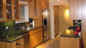 Une cuisine avec des meubles en bois, un réfrigérateur en acier inoxydable et un plan de travail en granit.