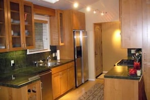 Eine Küche mit Holzschränken, einem Edelstahlkühlschrank und einer Arbeitsplatte aus Granit.