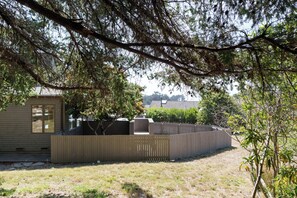 A fenced backyard with a wooden deck, a small shed, and a tree providing shade. - Sea Watch - Hot Tub & Ocean Deck Views (Sea Ranch)