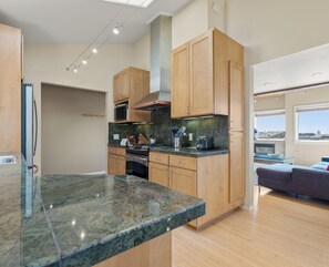 A modern kitchen with granite countertops, wooden cabinets, and stainless steel appliances. - Sea Watch - Hot Tub & Ocean Deck Views (Sea Ranch)