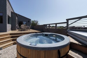 Ein Whirlpool auf einer Holterrasse mit Blick auf ein Gebäude im Hintergrund.