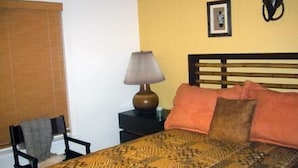 Une chambre à coucher avec un lit, une table de chevet avec une lampe, une chaise et un tableau accroché au mur.