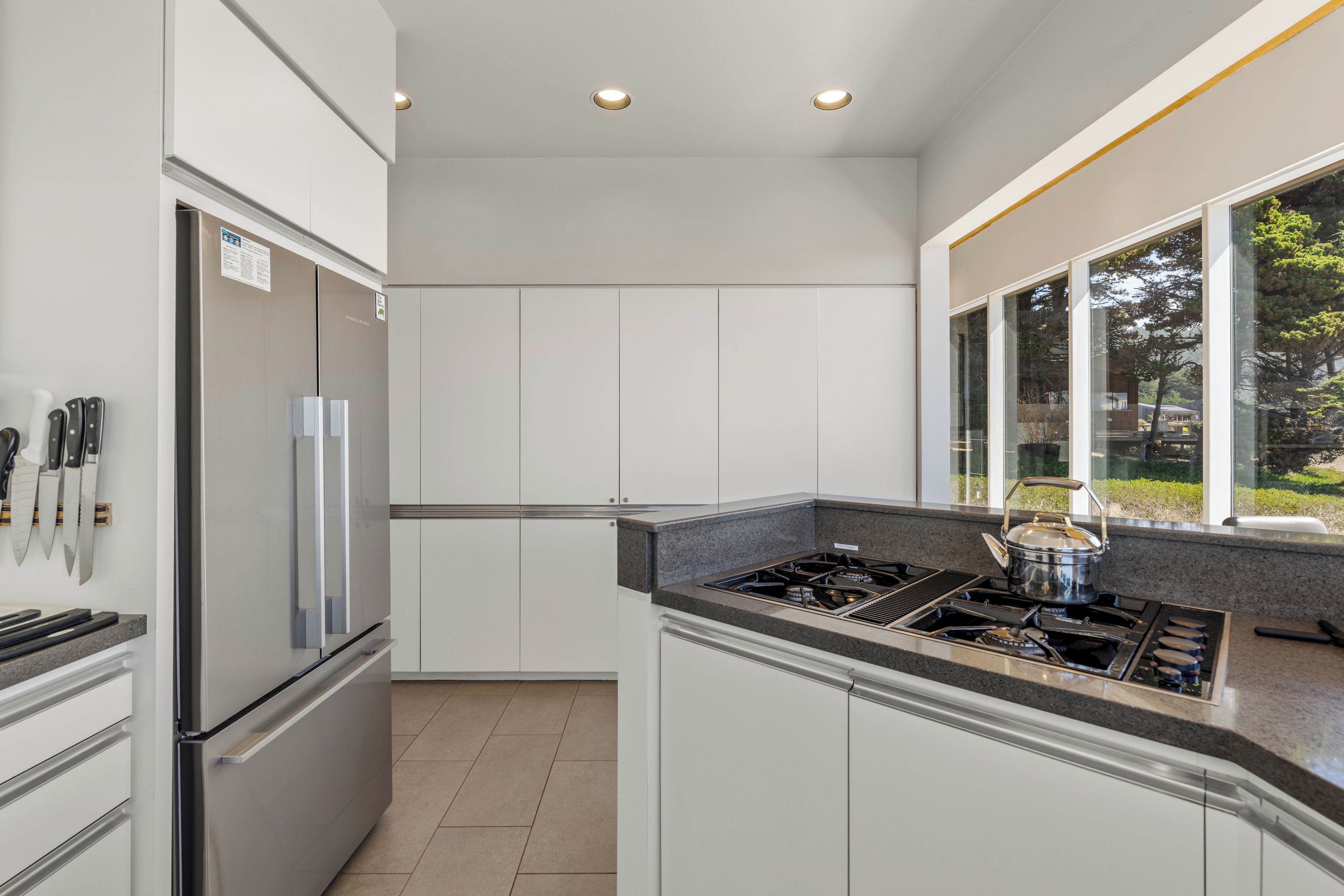 Una cucina moderna con mobili bianchi, un frigorifero in acciaio inossidabile e un piano cottura a gas.
