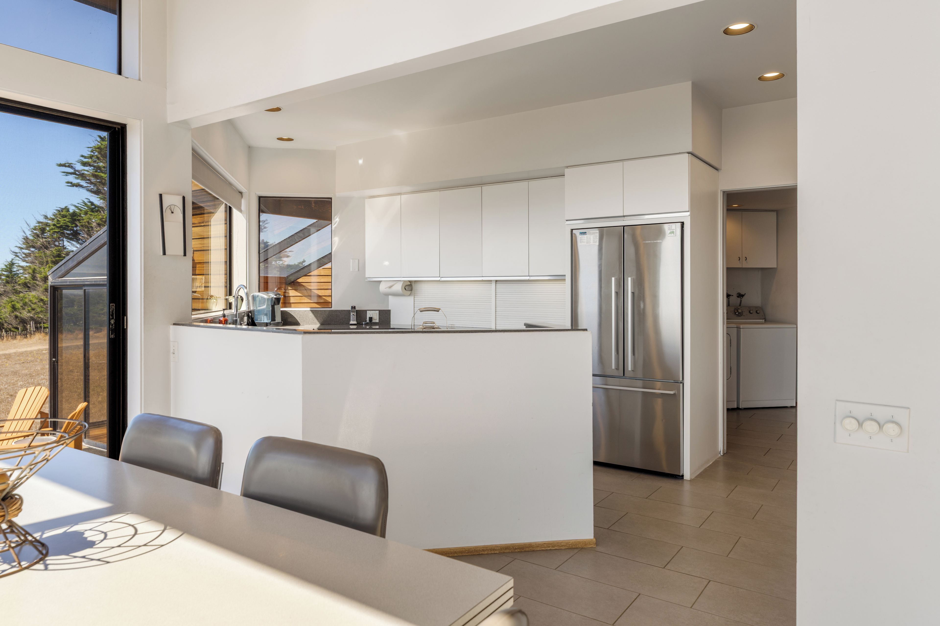 A modern kitchen with a central island, stainless steel appliances, and a dining area with a table and chairs.