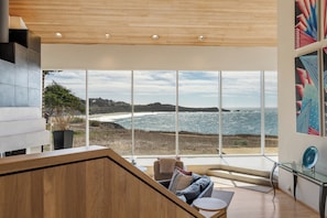 A modern interior with a large window overlooking a coastal view.